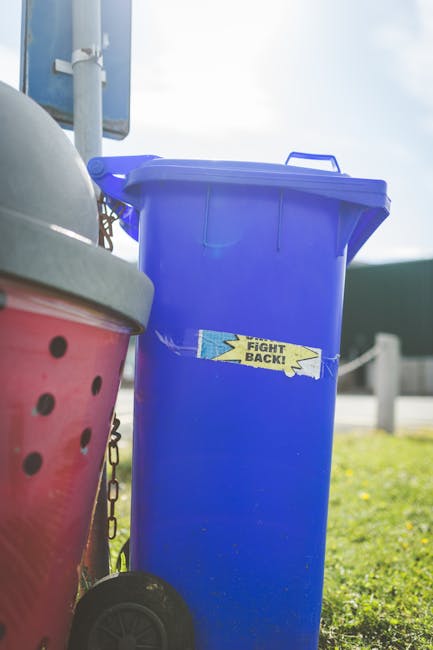 A rectangular white metal sign with bold black lettering mounted on a red brick wall. The sign reads 'NO DUMPING OF RUBBISH,' with the words arranged in three lines. The brick wall has a traditional r